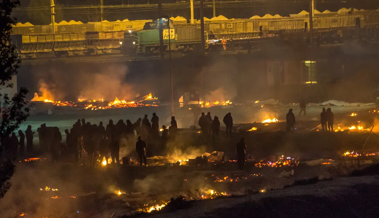 Imigran melihat sisa-sisa barang-barang mereka yang ludes terbakar di Dunkirk, Prancis, Senin (10/4).  Kamp penampungan imigran yang menampung sekitar 1500 orang itu ludes akibat kebakaran. (AFP PHOTO / PHILIPPE HUGUEN)