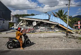 Sebuah sepeda motor berhenti di dekat bangunan yang runtuh pascagempa berkekuatan magnitudo 7,7 di Borong, Manggarai Timur, Nusa Tenggara Timur, Minggu, 16 Agustus 2026.. (AFP/ Juni Kriswanto)