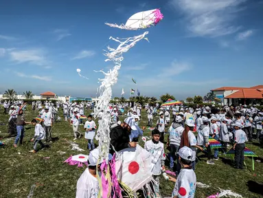 Anak-anak sekolah Palestina menerbangkan layangan dalam aksi solidaritas peringatan tujuh tahun gempa dan tsunami Jepang di Gaza, Selasa (13/3). Acara ini digagas oleh United Nations Relief and Works Agency (UNRWA). (SAID KHATIB/AFP)