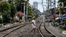 Seorang wanita melintasi rel kereta di kawasan pemukiman padat Pejompongan di tengah pandemi COVID-19, Jakarta, Kamis (28/1/2020). Sensus Penduduk 2020 (SP2020) mencatat penduduk DKI Jakarta pada bulan September 2020 sebanyak 10,56 juta  jiwa. (Liputan6.com/Johan Tallo)