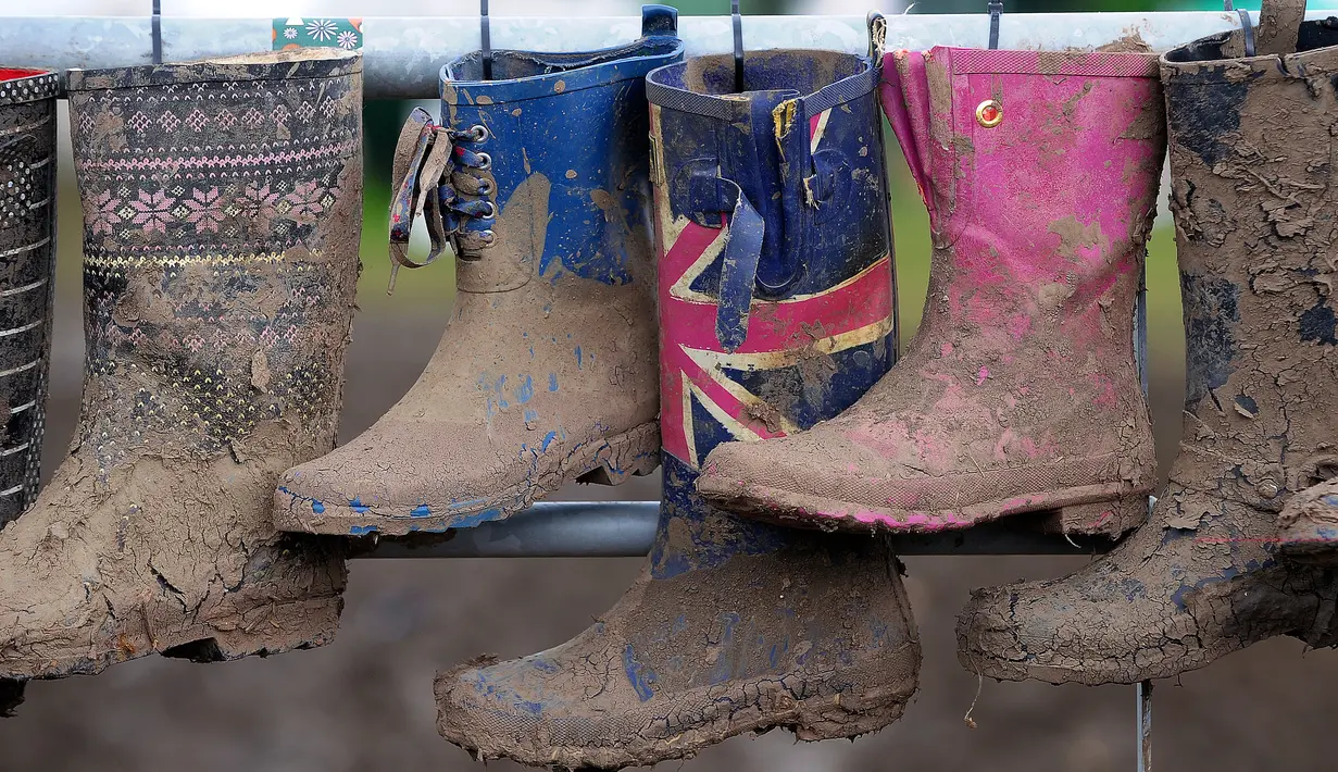 Sepatu boot berlumpur yang mengering tergantung pada hari kelima Festival Glastonbury di arena Worthy Farm, Inggris, 26 Juni 2017. Penyelenggaraan festival musik terbesar di dunia itu menyisakan sampah yang berserakan di seluruh arena. (Andy Buchanan/AFP)