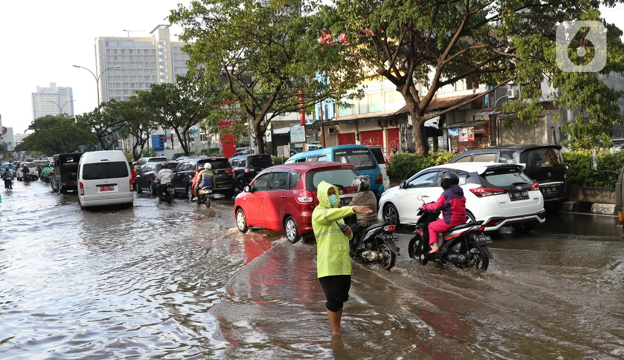 Polisi mengatur arus lalu lintas di jalan Margonda Raya yang tergenang air, Kota Depok, Jawa Barat, Jumat (29/5/2020). Tersumbatnya aliran air menyebabkan sebagian ruas jalan Margonda Raya sempat tergenang air serta menyebabkan arus lalu lintas tersendat. (LIputan6.com/Helmi Fithriansyah)