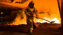 Seorang pekerja mengenakan pakaian pelindung mengambil cairan untuk membuat baja di Salzgitter, Jerman (22/3). Baja dibuat‎ dari hasil peleburan pasir besi, batu bara dan kapur dengan suhu di atas 1.000 derajat celciu‎s.  (AP Photo / Markus Schreiber)