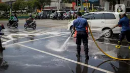 Sejumlah personil pemadam kebakaran membersihkan tumpah oli yang terjadi di Jalan Veteran depan Gedung Krida Bakti, Jakarta, Kamis (16/1/2020). Petugas damkar  melakukan pembersihan dengan cairan deterjen maupun campuran khusus agar jalan tersebut tidak lagi licin. (Liputan6.com/Faizal Fanani)