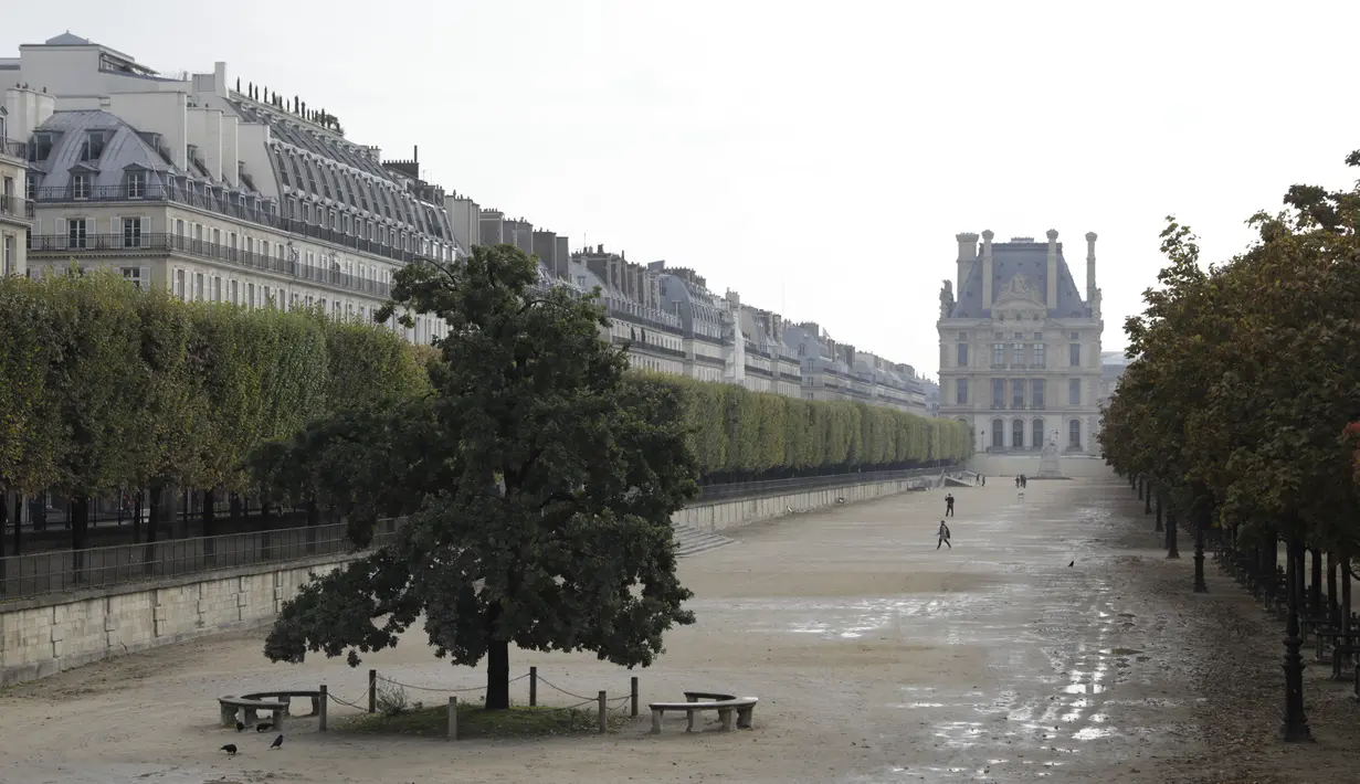 Orang-orang berjalan di taman Tuileries yang kosong di Paris (14/10/2020). Laporan media Prancis mengatakan Macron juga akan meningkatkan upaya di media sosial untuk mendesak perlunya perlindungan virus di kalangan anak muda. (AP Photo/Lewis Joly)