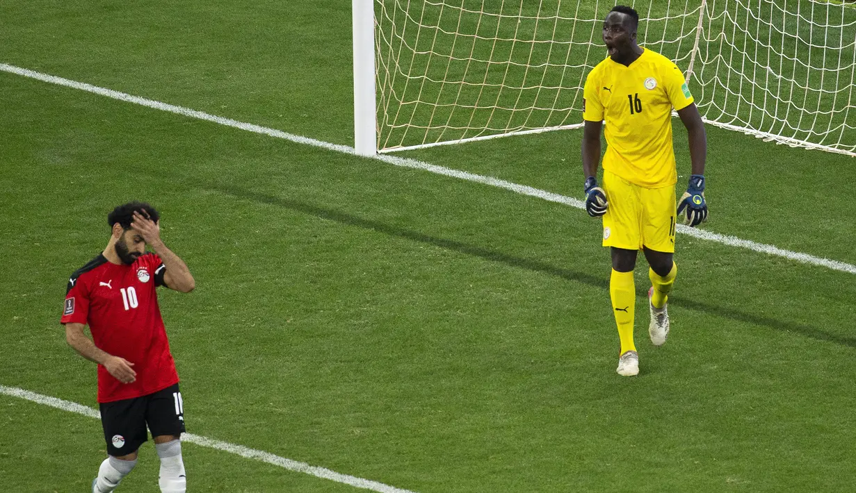 Reaksi penyerang Mesir Mohamed Salah (kiri) setelah gagal mencetak tendangan penalti ke gawang Senegal pada Kualifikasi Piala Dunia 2022 zona Afrika di Stade Me Abdoulaye Wade, Rabu (30/3/2022) dini hari WIB. Senegal menyingkirkan Mesir 3-1 lewat adu penalti. (AP Photo/Stefan Kleinowitz)