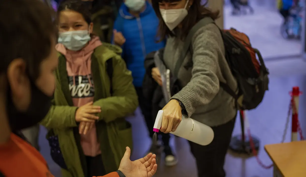 Siswa sekolah dasar mendisinfeksi tangan mereka saat melanjutkan aktivitas setelah liburan Natal di Barcelona, Spanyol, Senin (10/1/2022). Sekitar 8 juta siswa sekolah dasar dan menengah melanjutkan kelas setelah libur panjang Natal dan Tahun Baru. (AP/Emilio Morenatti)