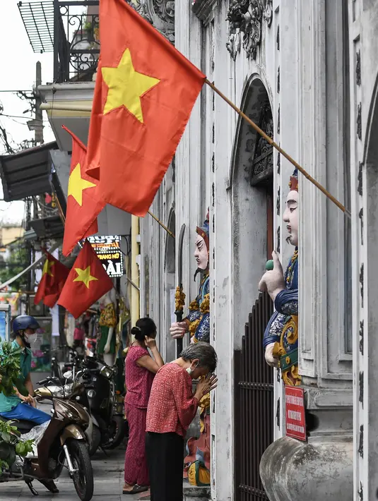 Umat Buddha berdoa di luar pagoda Cau Dong saat perayaan Hari Waisak di Hanoi, Vietnam pada Rabu (26/5/2021). Tempat ibadah di kawasan tersebut ditutup untuk mencegah penyebaran virus corona Covid-19. (Nhac NGUYEN / AFP)