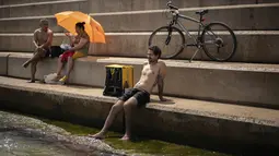 Seorang pengendara layanan pengiriman mendinginkan diri di tepi pantai di Barcelona, Spanyol, Sabtu (14/8/2021). Spanyol mengalami hari terpanas sepanjang tahun pada hari Sabtu dengan suhu mencapai 46 derajat Celcius. (AP Photo/Joan Mateu Parra)