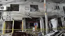 Petugas pemdam kebakaran memeriksa tempat kejadian setelah dugaan ledakan gas di jalanan ramai di Moghbazar, Dhaka, Bangladesh, Minggu (27/6/2021). Tujuh bangunan lain di dekatnya dan tiga bus hancur akibat ledakan. (Munir Uz zaman/AFP)