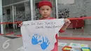Seorang bocah memegang spanduk bertuliskan anti korupsi saat acara peringatan anti korupsi 2015 LKPP, KPK, dan ICW bertajuk Hackathon Merdeka 3.0, Di LKPP Tower kawadan Rasuna Sahid, Jakarta, Sabtu (05/12). (Liputan6.com/Faisal R Syam)