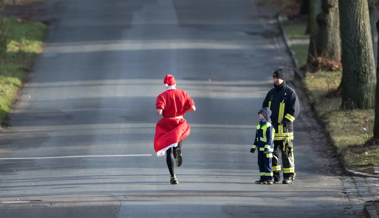 Seorang peserta berkostum Santa Claus berlari dalam kegiatan  Santa Claus Run di Michendorf, Jerman timur, Minggu (10/12). Kegiatan amal yang digelar setiap tahun ini diikuti ribuan warga Jerman dan wisatawan mancanegara. (Ralf Hirschberger / dpa / AFP)