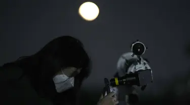 Seorang wanita mengambil foto bulan melalui teleskop saat gerhana bulan di Goyang, Korea Selatan, Selasa, 8 November 2022. Fenomena gerhana bulan total terjadi pada 8 November 2022 di berbagai negara. (AP Photo/Lee Jin-man)