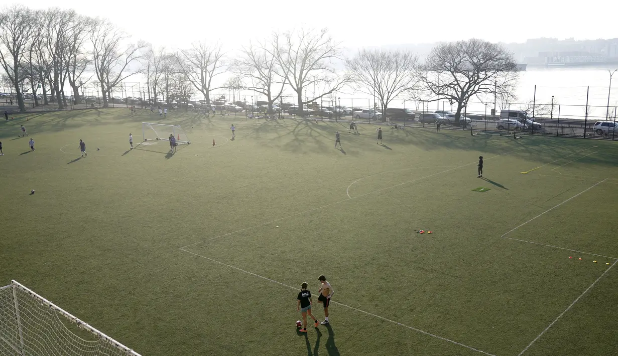 Orang-orang memanfaatkan cuaca hangat untuk bermain sepak bola di New York (11/3/2021).  Cuaca hangat yang tidak wajar membuat warga New York keluar setelah awal tahun bersalju. (AP Photo / Seth Wenig)