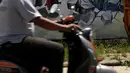 Pengendara motor melintas di depan mural bertema waspada COVID-19 di Jalan Baru, Depok, Jawa Barat, Selasa (7/4/2020). Sejumlah pesan disampaikan dengan beragam cara untuk mengingatkan masyarakat agar ikut serta dalam upaya memutus mata rantai penyebaran COVID-19. (Liputan6.com/Helmi Fithriansyah)