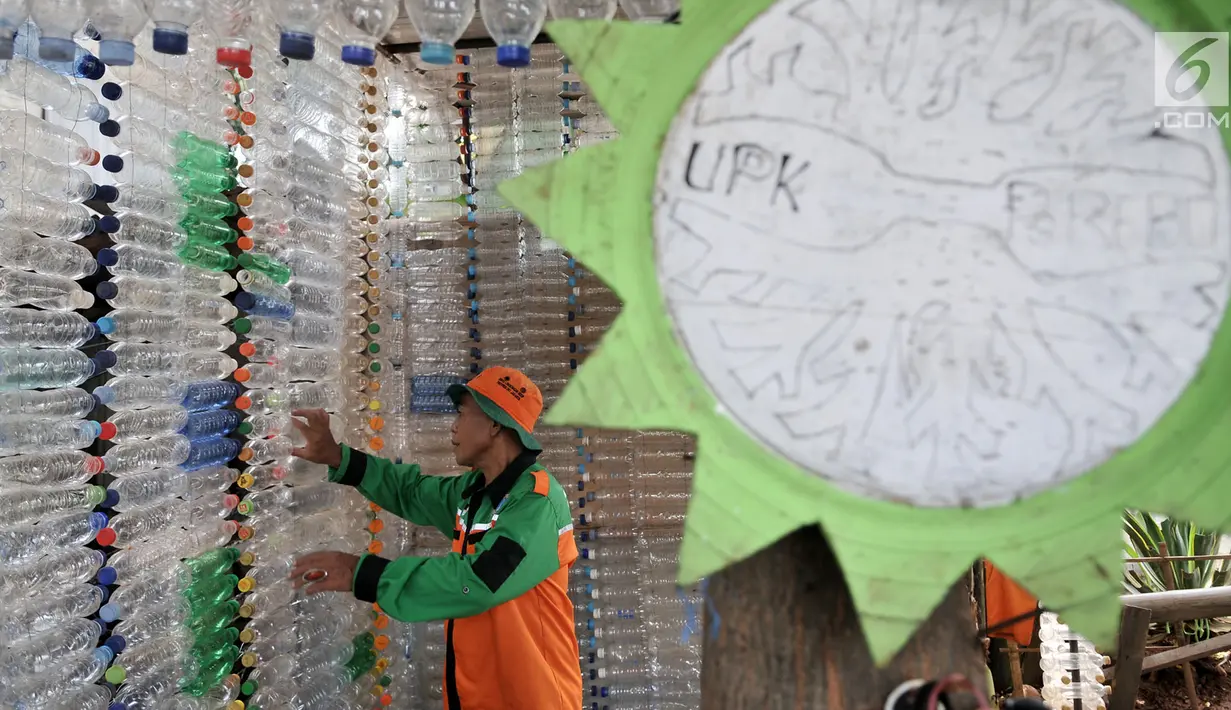 Petugas UPK Badan Air DLH DKI Jakarta saat merapikan susunan instalasi botol yang menghiasi pos di Pasar Rebo, Jakarta, Selasa (12/3). Petugas memanfaatkan botol plastik bekas untuk membangun pos cantik. (merdeka.com/Iqbal Nugroho)