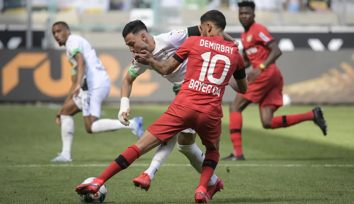 Pemain Bayer Leverkusen, Kerem Demirbay, berusaha menghadang pemain Borussia Moenchengladbach, Ramy Bensebaini, pada laga Bundesliga, Minggu (24/5/2020). Bayer Leverkusen menang 3-1 atas Borussia Moenchengladbach. (AFP/Ina Fassbender)