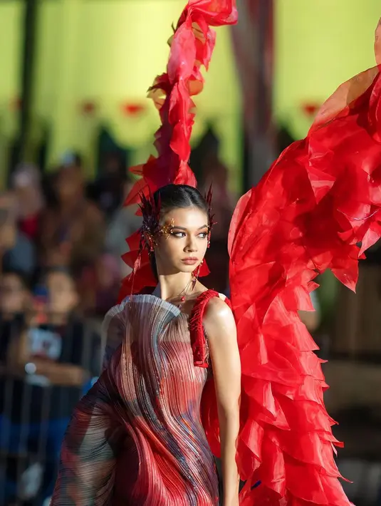 Yuki Kato tampil merah merona bak burung phoenix, mengenakan gaun dan sayap merah, serta makeup art deco yang seru. [Instagram/nasionp]