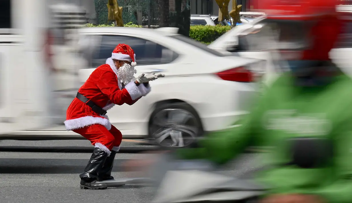 Petugas lalu lintas, Ramiro Hinojas mengenakan kostum sinterklas sambil mengarahkan kendaraan di sepanjang Macapagal Avenue di Pasay, Metro Manila, Filipina pada 28 November 2023. (JAM STA ROSA/AFP)