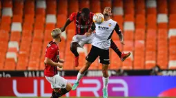 Bek AC Milan, Fode Ballo-Toure (tengah) berebut bola dengan gelandang Valencia, Jason (kanan) selama pertandingan persahabatan di Stadion Mestalla di Valencia (4/8/2021). Bermain imbang 0-0 di waktu normal, AC Milan kalah atas Valencia lewat adu penalti 5-3. (AFP/Jose Jordan)