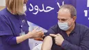 Seorang pria Israel menerima dosis keempat vaksin covid-19 Pfizer-BioNTech di Sheba Medical Center di Ramat Gan dekat Tel Aviv, Senin (27/12/2021). Israel memulai uji coba pemberian vaksin virus corona dosis keempat kepada 150 tenaga medis sebuah rumah sakit. (AP Photo/Tsafrir Abayov)