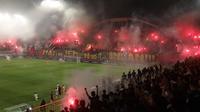 Suporter PSS Sleman menyalakan flare saat bersua Persija Jakarta pada laga pekan ke-33 BRI Liga 1 musim ini di Stadion Maguwoharjo, Sleman, Sabtu (17/5/2025) malam WIB. Meski sempat dihentikan gara-gara asap flare, PSS berhasil menang 2-1 atas Persija. (Bola.com/Ana Dewi)