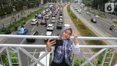 Seorang pejalan kaki berswafoto di jembatan penyeberangan orang (JPO) yang tidak beratap di jalan Sudirman, Jakarta, Rabu (6/11/2019). Pemprov DKI mengklaim mayoritas masyarakat Jakarta setuju dengan konsep JPO terbuka dan tanpa atap yang kini dibangun di Sudirman. (merdeka.com/Arie Basuki)
