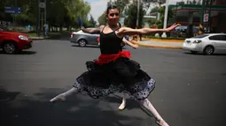 Balerina menampilkan tarian balet saat lampu merah di tengah jalanan Mexico City, 28 Juli 2018. Sejak pertunjukkan dimulai dua minggu lalu, para penari telah menarik perhatian fotografer, videografer, dan bahkan operator drone. (AP/Emilio Espejel)