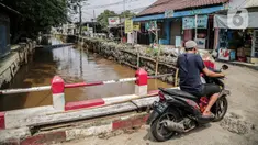 Pengendara motor melintas dekat bantaran Kali Induk Kramat Jati, Jakarta, Rabu(18/5/2022). Pemprov DKI Jakarta melalui Dinas Sumber Daya Air (SDA) berencana akan menormalisasi Kali Induk secara keseluruhan guna mencegah banjir yang melanda kawasan tersebut saat hujan deras mengguyur. (Liputan6.com/FaizaL Fanani)