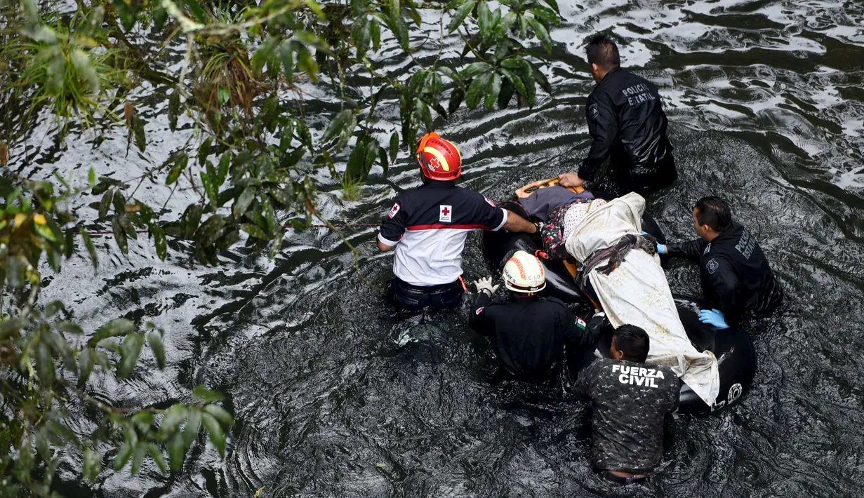 Petugas membawa tandu yang berisi korban jatuhnya bus ke jurang  dari sebuah jembatan di Negara Bagian Veracruz, selatan Meksiko, Minggu (10/1). Sedikitnya 20 orang penumpang tewas dalam kecelakaan ini. (REUTERS/Yahir Ceballos)