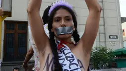 Aktivis memborgol tangan sambil bertelanjang dada saat menggelar aksi Hari Internasional untuk Penghapusan Kekerasan terhadap Perempuan di Lima, Peru, Rabu (25/11). Mereka menuntut legalisasi aborsi dalam kasus pemerkosaan. (AFP PHOTO/CRIS BOURONCLE)