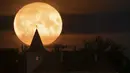 Bulan purnama muncul di atas sebuah rumah pribadi di desa Putilovo, 70 kilometer (43 mil) timur St. Petersburg, Rusia, Rabu malam (13/7/2022). Bulan Purnama dikenal sebagai Buck Moon dan juga Supermoon. Fenomena tersebut hanya terjadi setiap 9 tahun sekali, dan terakhir kali muncul pada 2013 lalu. (AP Photo/Dmitri Lovetsky)