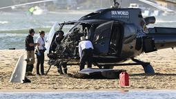 Petugas darurat memeriksa helikopter di lokasi tabrakan dekat Seaworld, di Gold Coast, Australia, Senin, 2 Januari 2023. Dua helikopter bertabrakan di udara menewaskan empat orang termasuk sepasang suami istri dari Inggris dalam kecelakaan yang menarik bantuan darurat dari pengunjung pantai selama musim panas. (Dave Hunt/AAP Image via AP)
