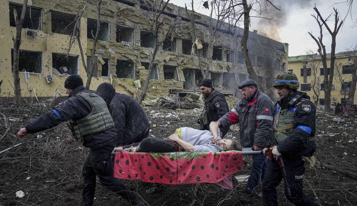 <p>Pekerja dan relawan darurat Ukraina membawa seorang wanita hamil yang terluka dari rumah sakit bersalin yang rusak akibat serangan udara di Mariupol, Ukraina (9/2/2022). (AP Photo/Evgeniy Maloletka)</p>