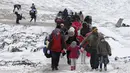 Sejumlah keluarga berjalan melewati salju tebal setelah melintasi perbatasan Macedonia di dekat desa Miratovac, Serbia, (18/1/2016). (REUTERS/Marko Djurica)
