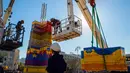 Pekerja dan relawan menggunakan alat berat saat menyusun kepingan LEGO untuk membuat menara di Lapangan Rabin di Tel Aviv, Israel, Rabu (27/12). Menara LEGO ini juga dibuat untuk memecahkan Guinness World Record. (AFP Photo/Jack Guez)