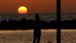 Seorang warga menyaksikan matahari terbenam di kota pesisir Mediterania Israel Netanya, utara Tel Aviv (8/6/2021). Kota ini memiliki penduduk sebanyak 173.300. (AFP/ Jack Guez)