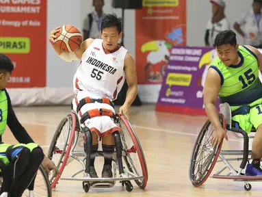 Pebasket difable Indonesia, Donald P Santoso (tengah) mencoba menembus kawalan pemain Malaysia pada laga Indonesia Para Games Invitational Tournament 2018 di Hall A Senayan, Jakarta, Minggu (1/7). Indonesia unggul 54-53. (Liputan6.com/Helmi Fithriansyah)