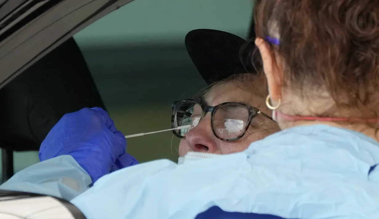 Seorang pria diambil sampel di klinik pengujian COVID-19 drive-thru di Pantai Bondi di Sydney, Sabtu (8/1/2022). Negara bagian terpadat di Australia itu memberlakukan kembali beberapa pembatasan dan menangguhkan operasi elektif ketika kasus COVID-19 melonjak ke rekor lain. (AP Photo/Mark Baker)