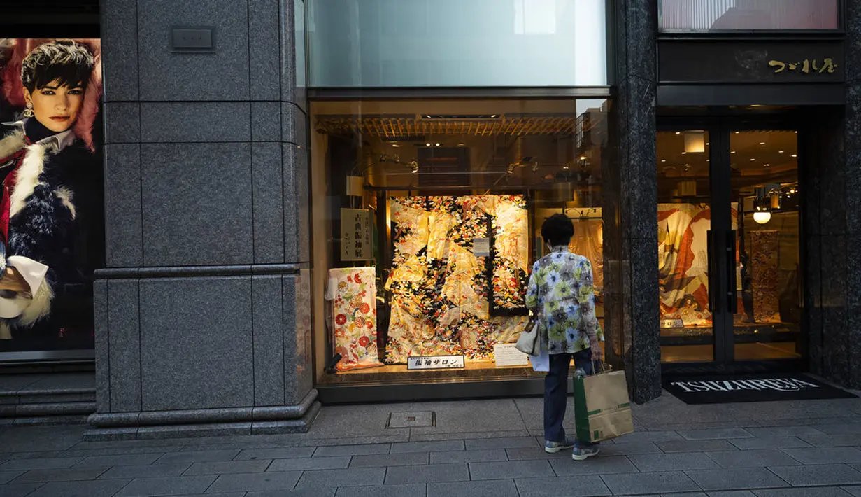 Seorang pejalan kaki berhenti untuk melihat tampilan kimono di distrik perbelanjaan Ginza Tokyo, Kamis (23/9/2021). Kawasan ini disebut Ginza karena dulunya di tempat ini terdapat percetakan uang logam perak yang dibangun tahun 1612 (zaman Edo). (AP Photo/Hiro Komae)