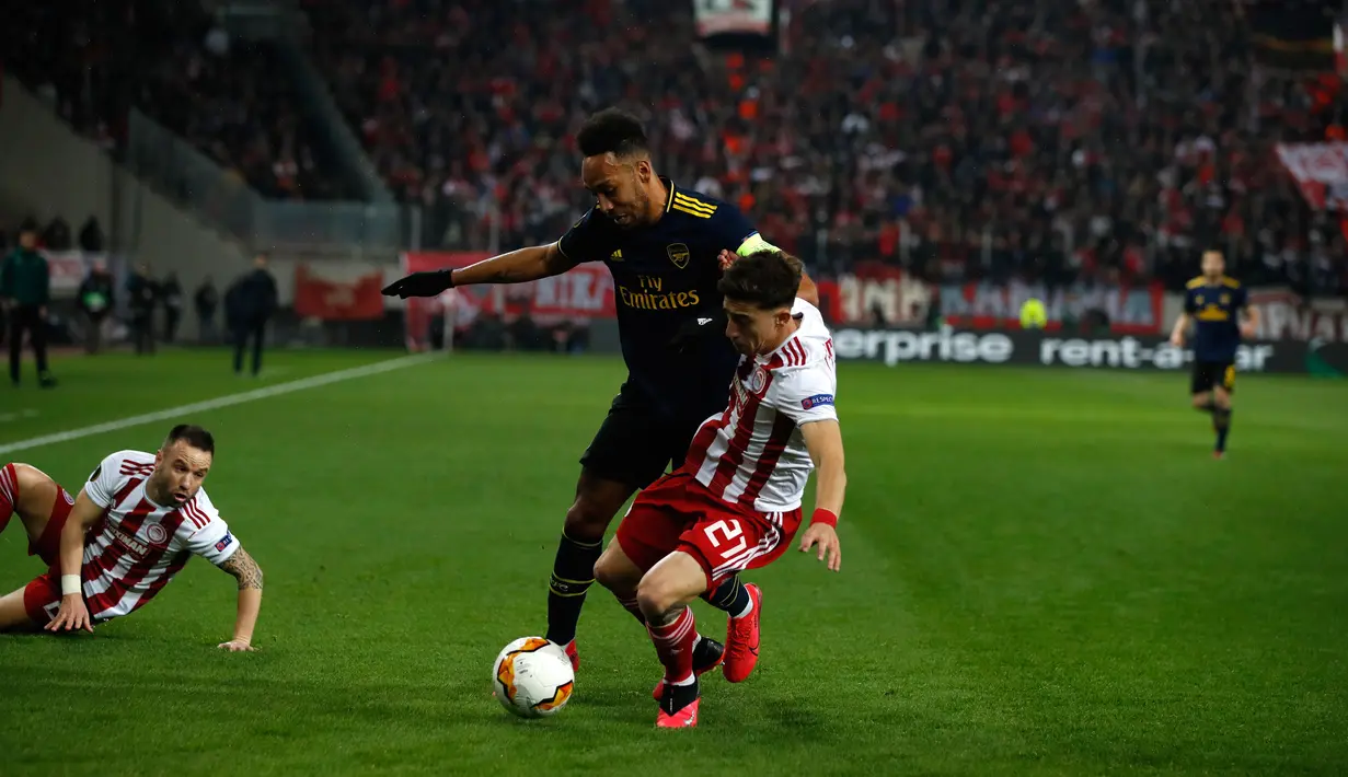Striker Arsenal, Pierre Emerick Aubameyang berebut bola dengan pemain Olympiakos Piraeus, Kostas Tsimikas pada leg pertama babak 32 besar Liga Europa di Georgios Karaiskakis Stadium, Kamis (20/2/2020). Arsenal susah payah menaklukkan Olympiakos Piraeus 1-0. (AP/Thanassis Stavrakis)
