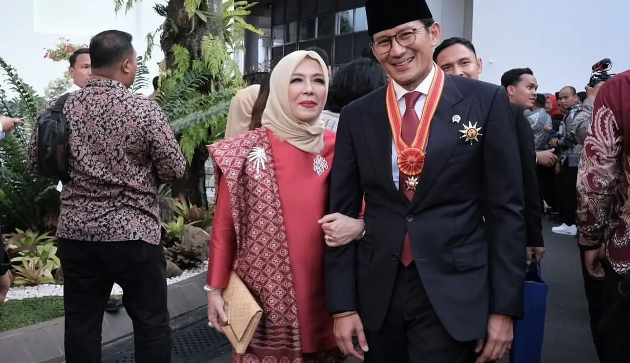 Berbeda dengan penampilan Nur Asia yang memilih berkebaya merah polos dengan sentuhan kain batik sebagai selendang, yang senada, dan dua bros silver yang disematkan di bagian dadanya. [Foto: Instagram/sandiuno]