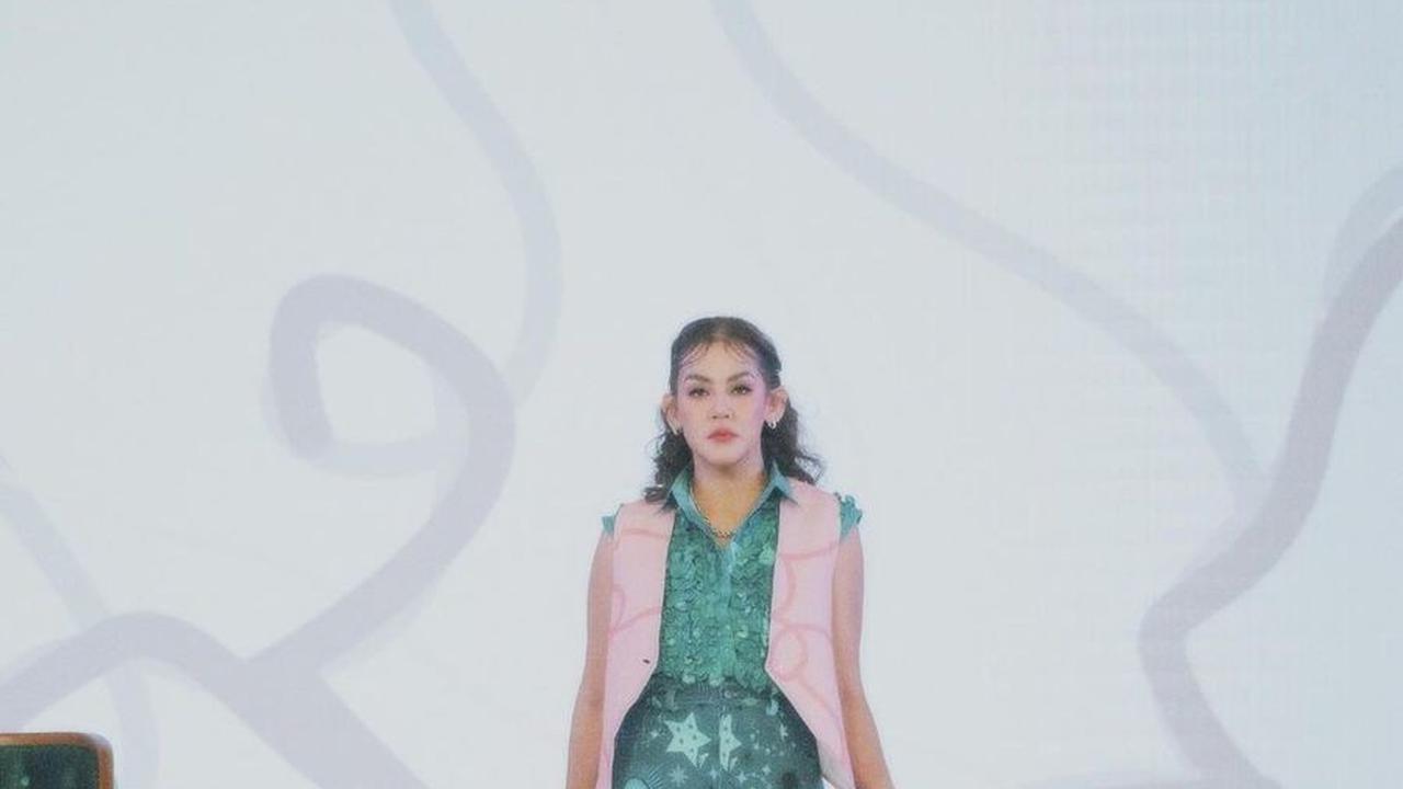 Sissy melangkah dengan penuh percaya diri mengenakan busana bernuansa hijau dan pink, tampil anggun di atas catwalk. Rambutnya pun ditata rapi dengan poni estetik yang menambah pesonanya.<br><br>