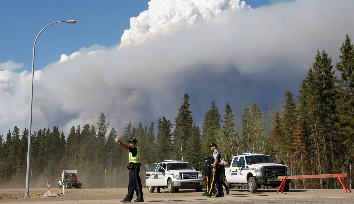 Petugas berjaga di kawasan dekat dari kepulan asap yang membakar hutan di wilayah Fort McMurray, Alberta, Kanda, 4 Mei 2016. Kebakaran ini merupakan yang terbesar kedua di wilayah tersebut dalam setahun. (REUTERS / Topher Seguin)