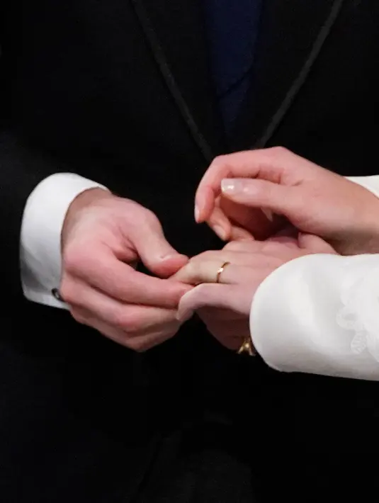Jack Brooksbank memasang cincin di jari Putri Eugenie saat upacara pernikahan mereka di Kapel St. George, Windsor Castle, London, Inggris,  Jumat (12/10). Ada 850 orang penting yang masuk ke daftar utama tamu undangan. (Danny Lawson/Pool via AP)