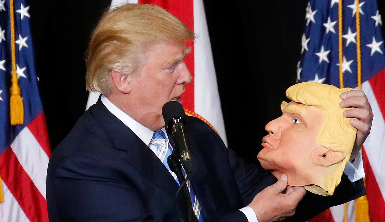 Capres dari Partai Republik Donald Trump melihat topeng wajah dirinya saat berkampanye di Sarasota, Florida, AS (7/11). Pilpres AS 2016 akan diadakan pada 8 November 2016 dan menjadi pilpres empat tahunan ke-58.  (REUTERS/Carlo Allegri) 