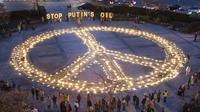 Orang-orang berdiri sekitar tanda perdamaian raksasa dengan pesan 'Hentikan Minyak Putin' jelang KTT Uni Eropa dan NATO di Brussels, Belgia, 22 Maret 2022. Pengunjuk rasa meminta para pemimpin Uni Eropa memberlakukan larangan penuh terhadap bahan bakar Rusia. (AP Photo/Geert Vanden Wijngaert)