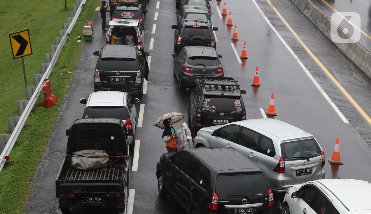 Seorang pedagang asongan menawarkan dagangan kepada pengendara di jalan tol Jagorawi yang sedang menanti waktu buka tutup jalur menuju kawasan wisata puncak, Bogor, Jawa Barat, Sabtu (31/10/2020). (Liputan6.com/Helmi Fithriansyah)