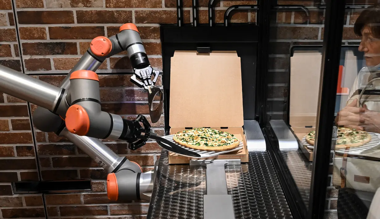 Foto pada 1 Juli 2021 menunjukkan "Pazzi", robot pembuat pizza sedang bekerja di sebuah restoran di Paris. Restoran kecil Pazzi di distrik Beaubourg adalah yang kedua dibuka, setelah di pusat perbelanjaan Val d'Europe yang dibuka pada November 2019 lalu. (BERTRAND GUAY/AFP)