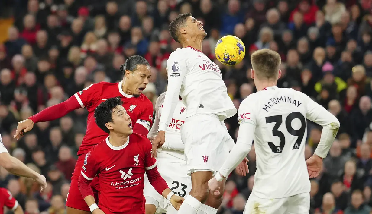 <p>Pemain Manchester United, Raphael Varane (tengah) berusaha menghalau bola saat laga lanjutan Liga Inggris 2023/2024 melawan Liverpool di Anfield, Liverpool, Inggris, Rabu (18/12/2023) dini hari WIB. (AP Photo/Jon Super)</p>